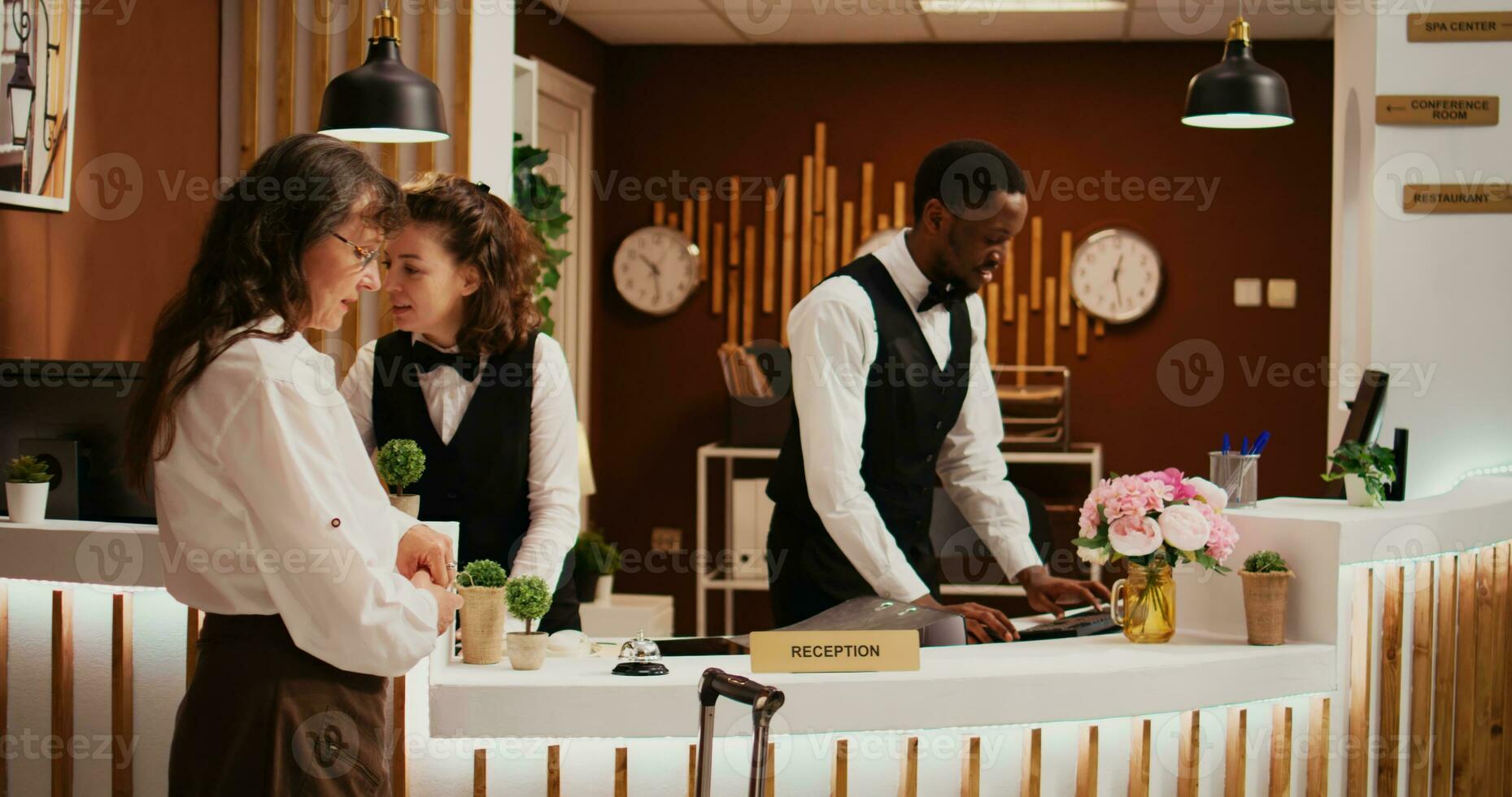 vieux femme en utilisant un service cloche à bague pour assistance, Hôtel client appel pour de face bureau Personnel à aller par vérifier dans processus sur vacances. touristique parlant à des employés à propos tout compris des offres. photo