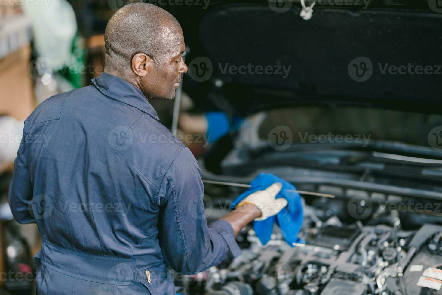 le réparateur de voitures vérifie le niveau d'huile moteur dans l'atelier  automobile, l'inspection des travailleurs de la voiture d'entretien  contrôle les moteurs de véhicules à huile par test de jauge à la