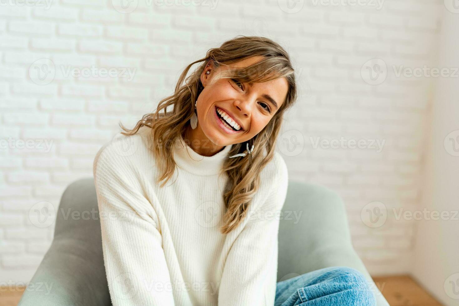 intérieur hiver portrait de jolie femme dans confortable chandail assis sur moderne canapé à maison. photo