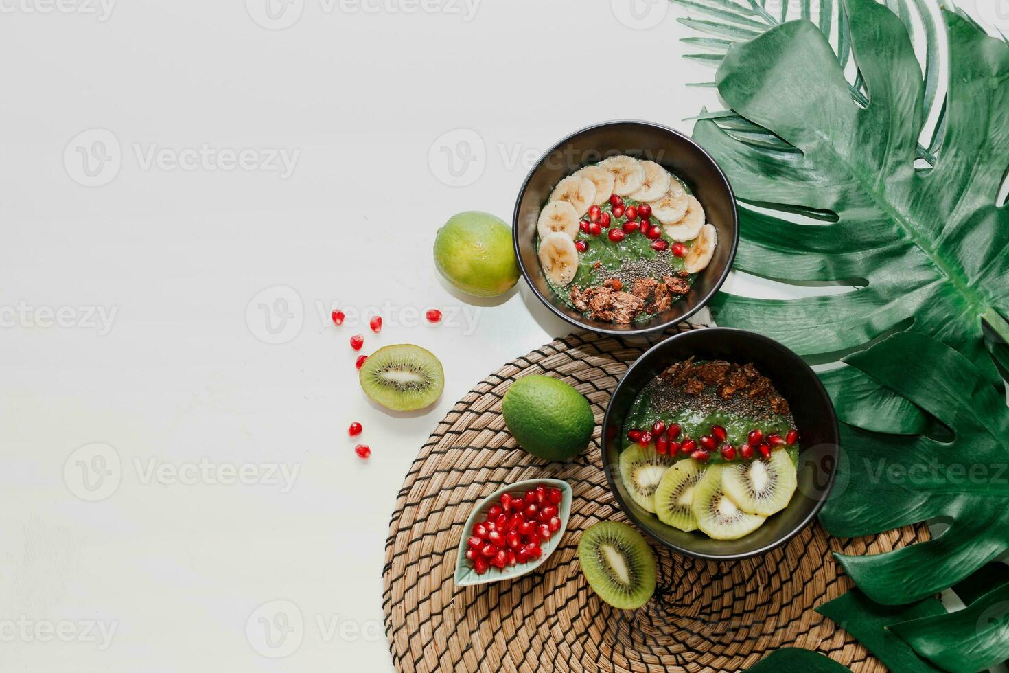 en bonne santé nourriture concept. Haut vue sur table avec smoothie boules. assiette surmonté avec kiwi, granola, grenat, chia, Avocat. tropical feuilles sur Contexte. copie espace. photo