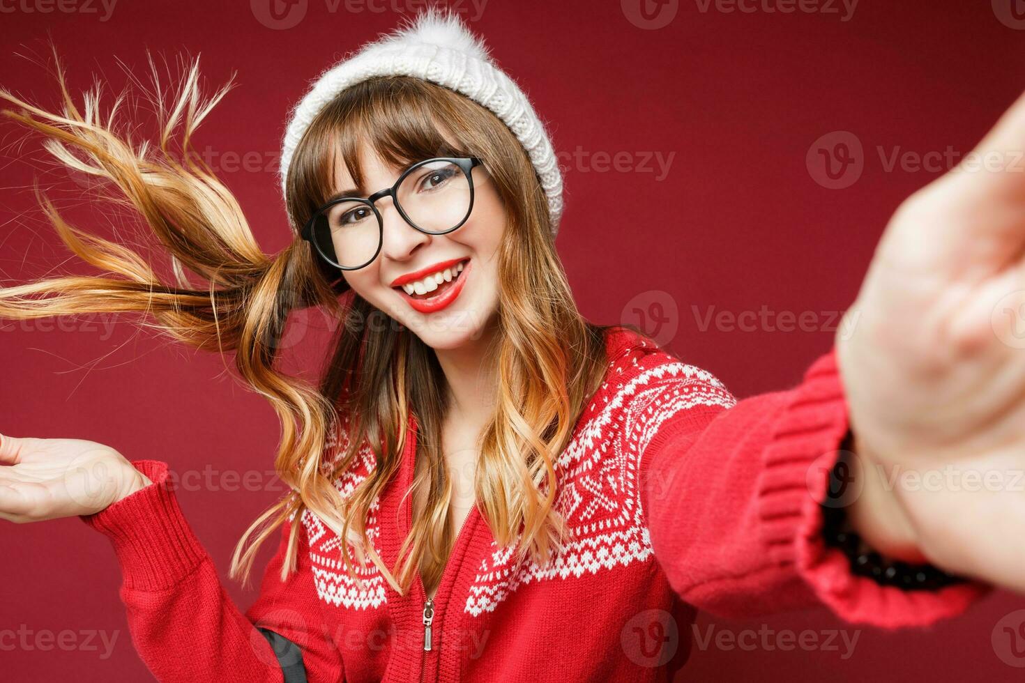 souriant femme dans hiver tenue posant dans studio sur rouge Contexte. photo