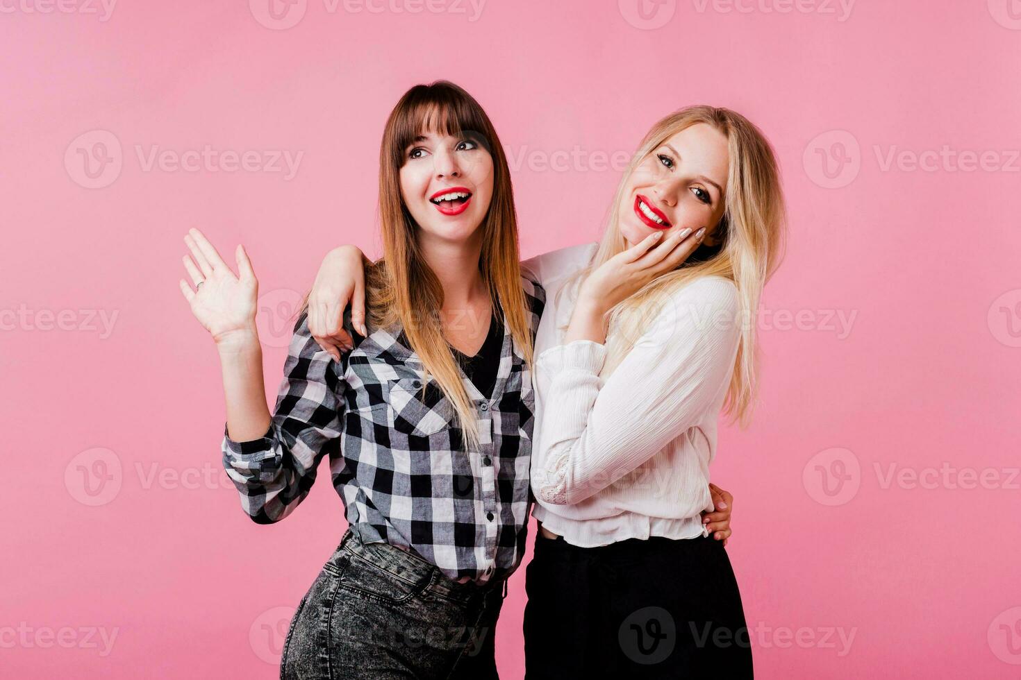 deux souriant femmes étreindre et permanent isoler plus de rose Contexte . brunette et blond filles. Naturel faire en haut. photo