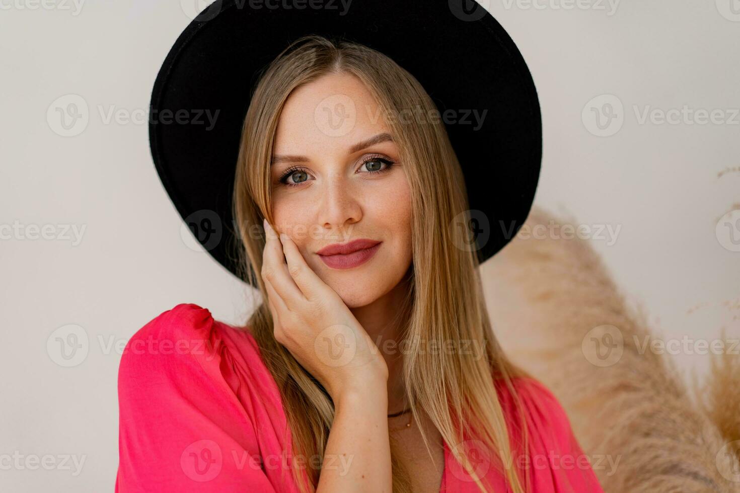 proche en haut portrait blond femme dans noir chapeau et encre robe posant dans studio dans studio avec pampa herbe décor. photo