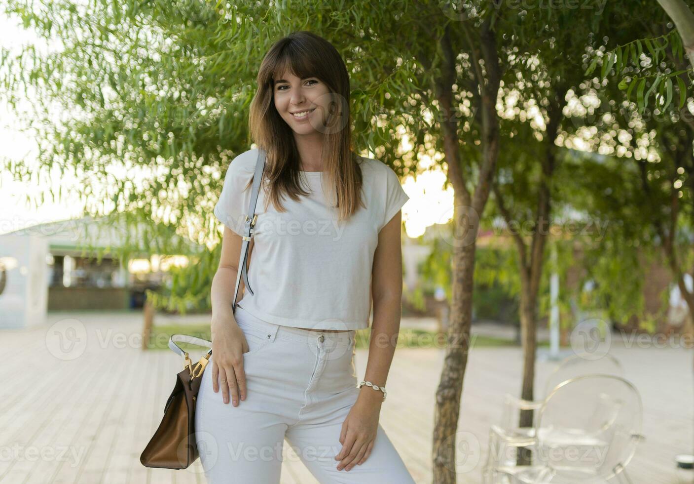 Extérieur portrait de de bonne humeur femme dans blanc T-shirt et jeans en marchant dans le parc. photo