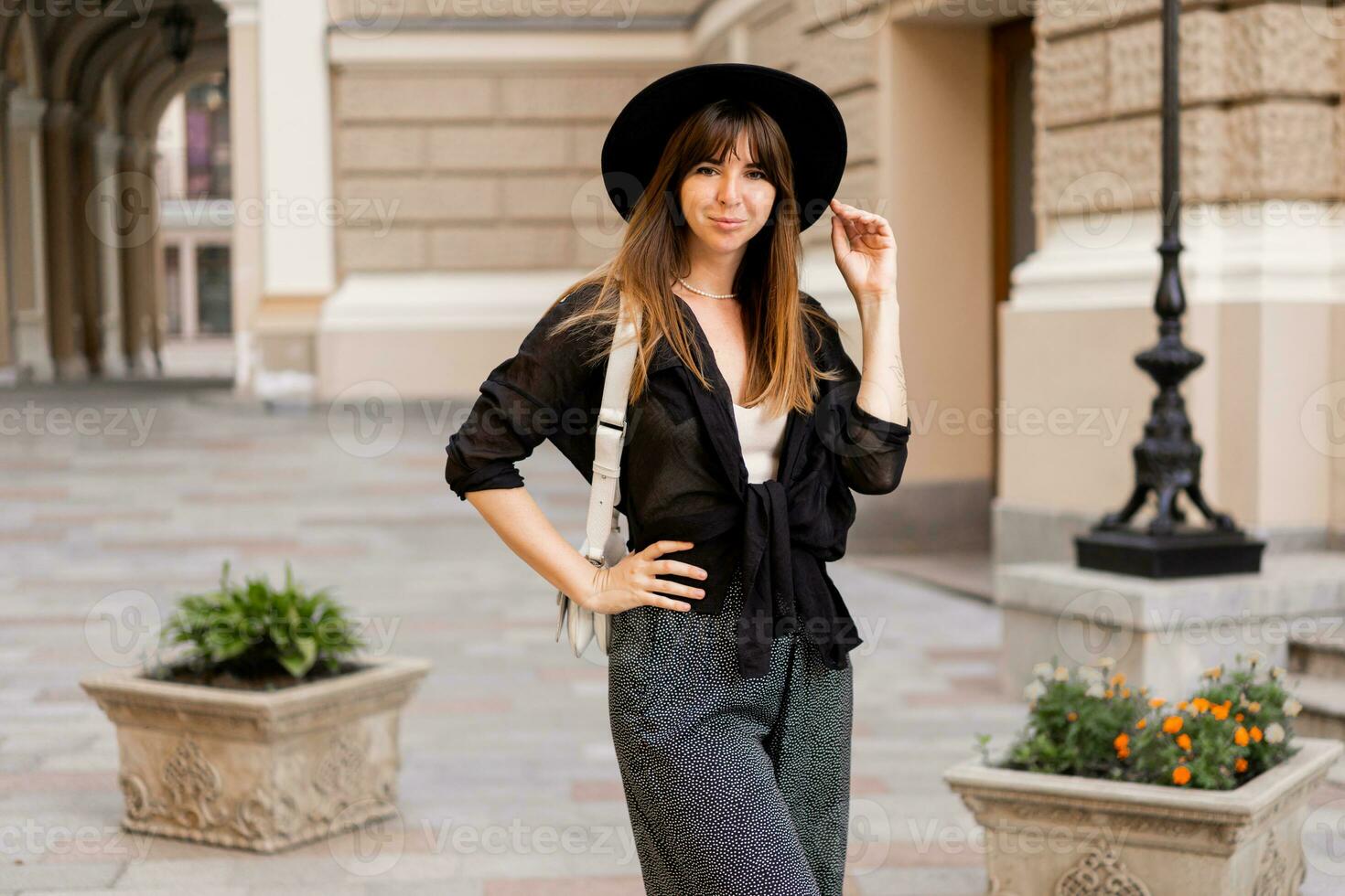 rue mode photo de élégant brunette femme dans décontractée tenue et noir chapeau. enjoing vacances dans européen ville.