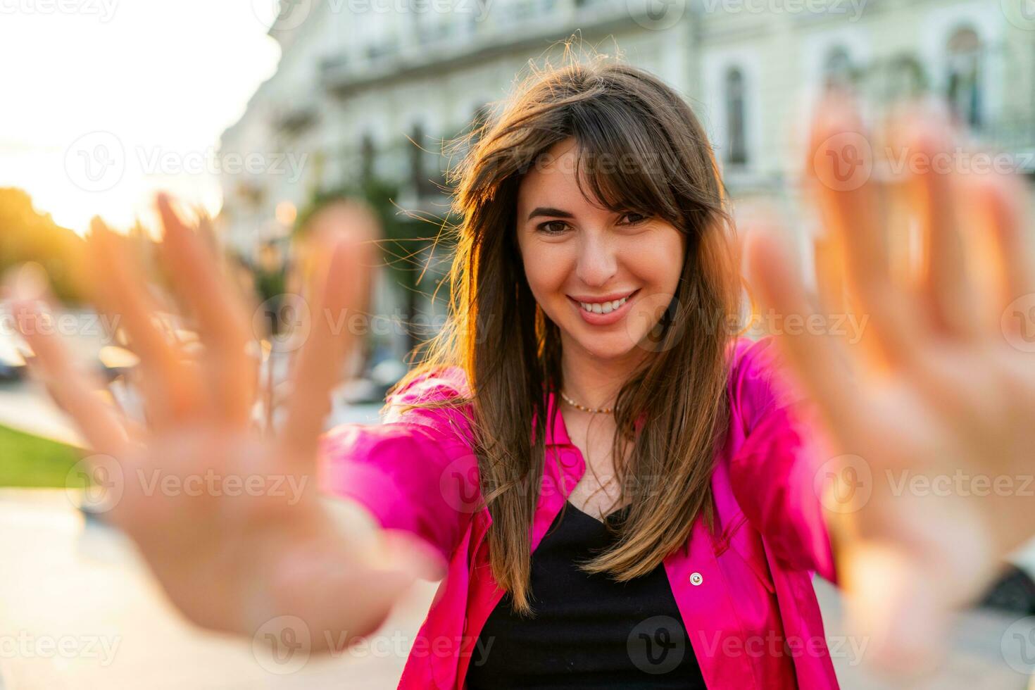 Extérieur été portrait de débonnaire bien regarder femme dans élégant rose merdique. européen rue sur Contexte. chaud le coucher du soleil couleurs. photo