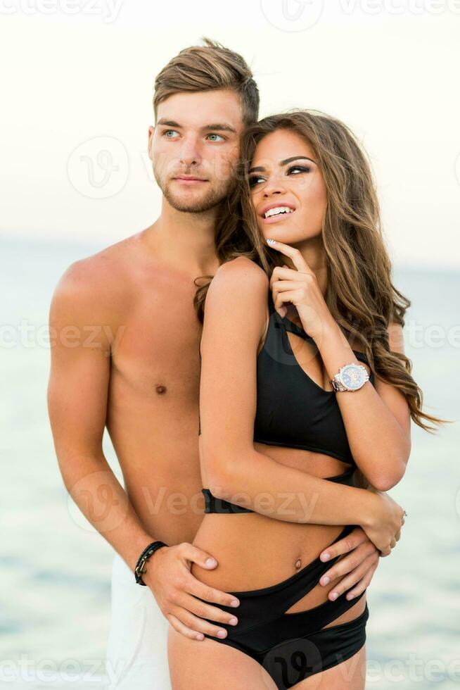 Extérieur proche en haut mode portrait de jolie sexy couple dans l'amour câlins sur incroyable tropical plage, portant élégant maillots de bain. photo