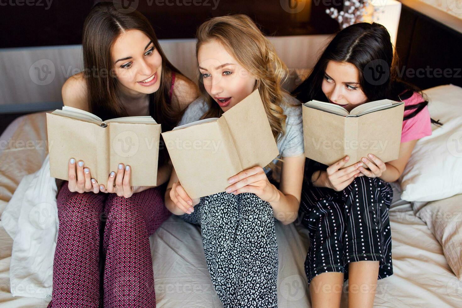 mode de vie image de Trois meilleur copains dans pyjamas en train de lire livres, en train d'étudier et conversations dans chambre à coucher. groupe de élèves Faire devoirs ensemble à maison. confortable chaud couleurs. émotif visages. photo