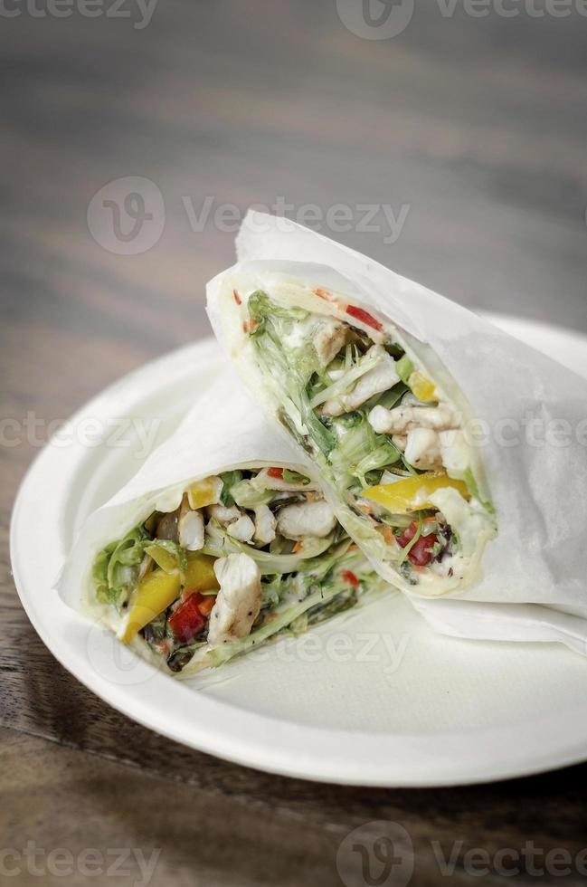 Wrap de salade de poulet bio en papier blanc sur fond de table en bois photo