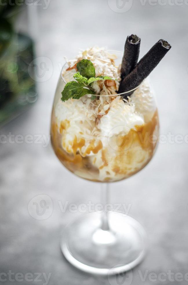 Noix de coco biologique gastronomique et caramel avec dessert sundae à la crème glacée dans un verre à vin photo