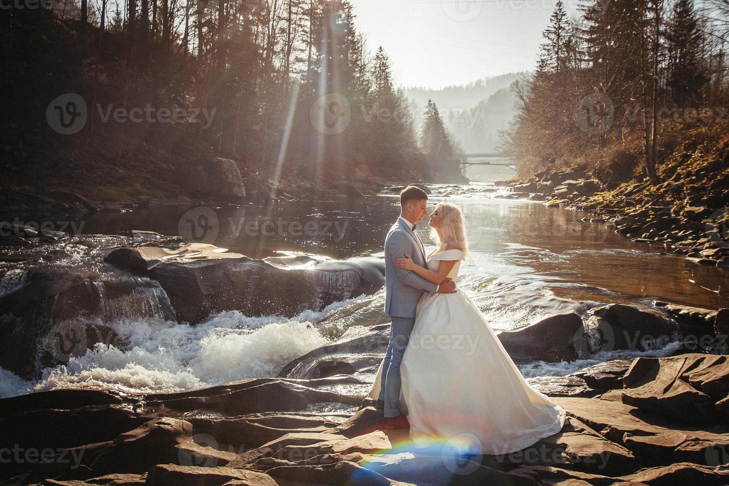 couple de mariage sur un fond de montagnes et de rivières dans les couchers de soleil photo