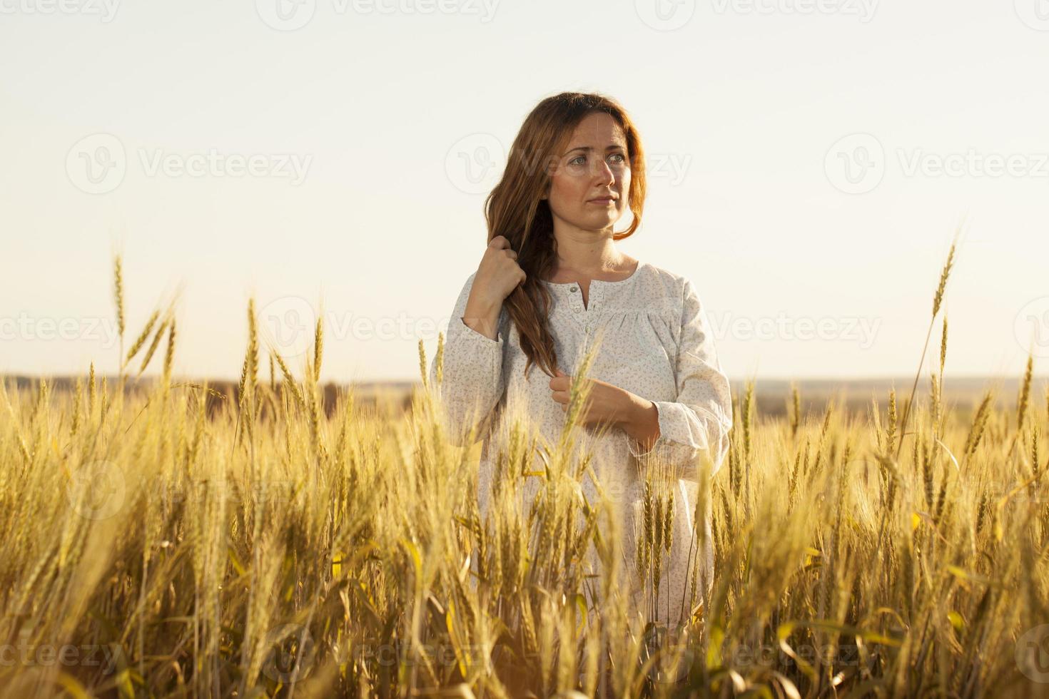 jeune femme se tient au milieu d'un champ de blé photo