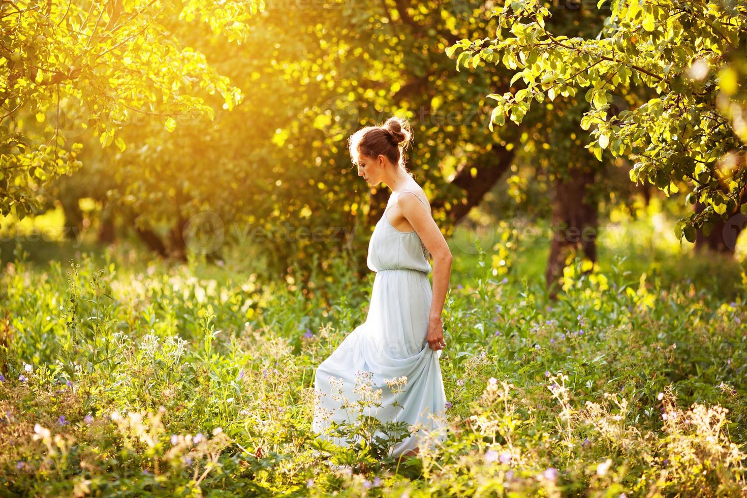 femme en robe se promène dans un verger de pommiers photo