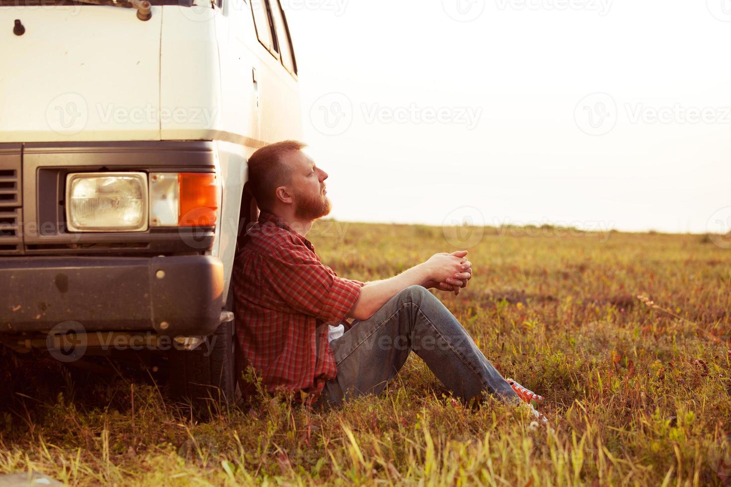 conducteur se reposant dans un champ près de sa voiture photo