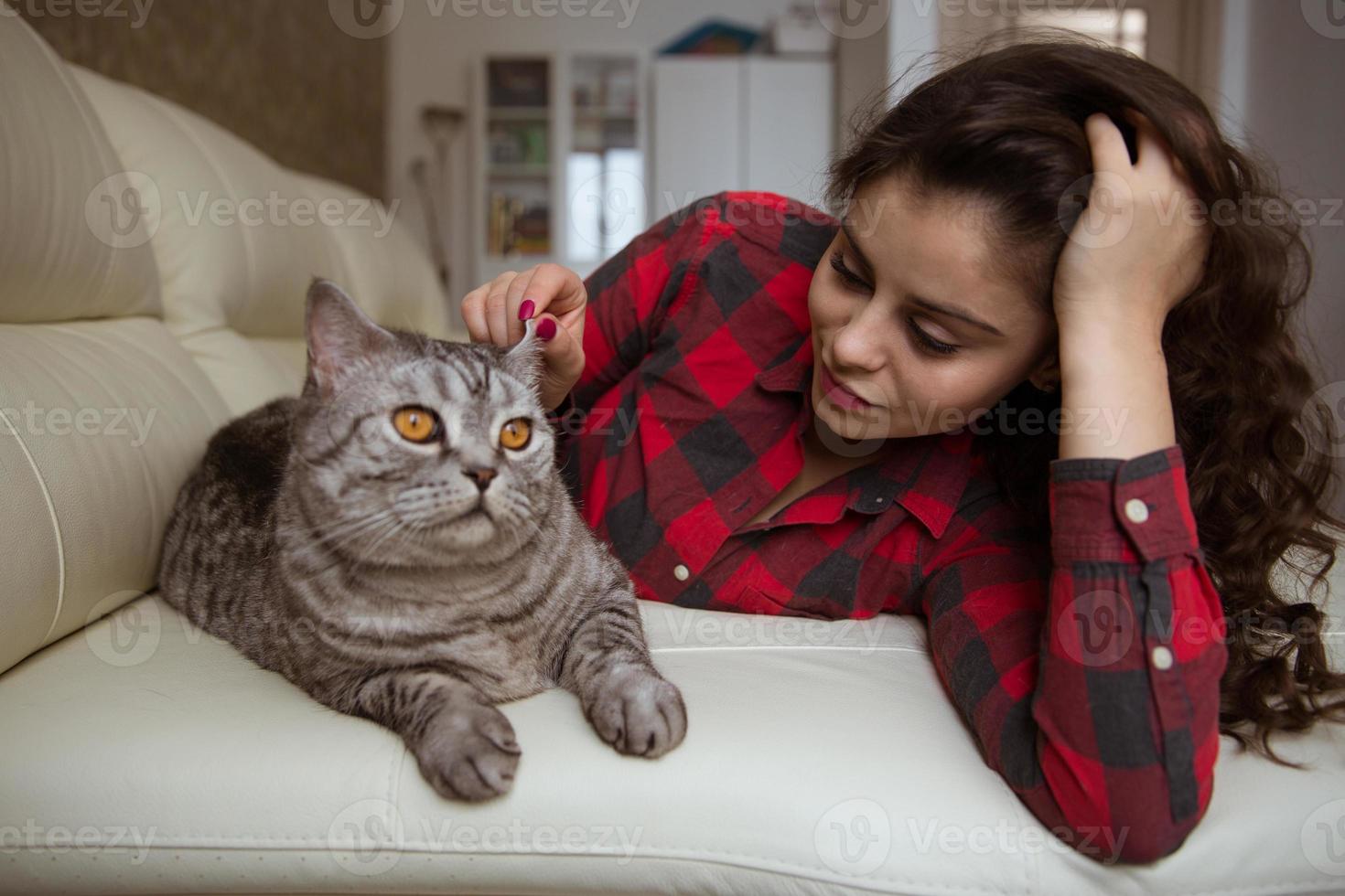 belle fille est allongée sur le canapé avec un gros chat photo