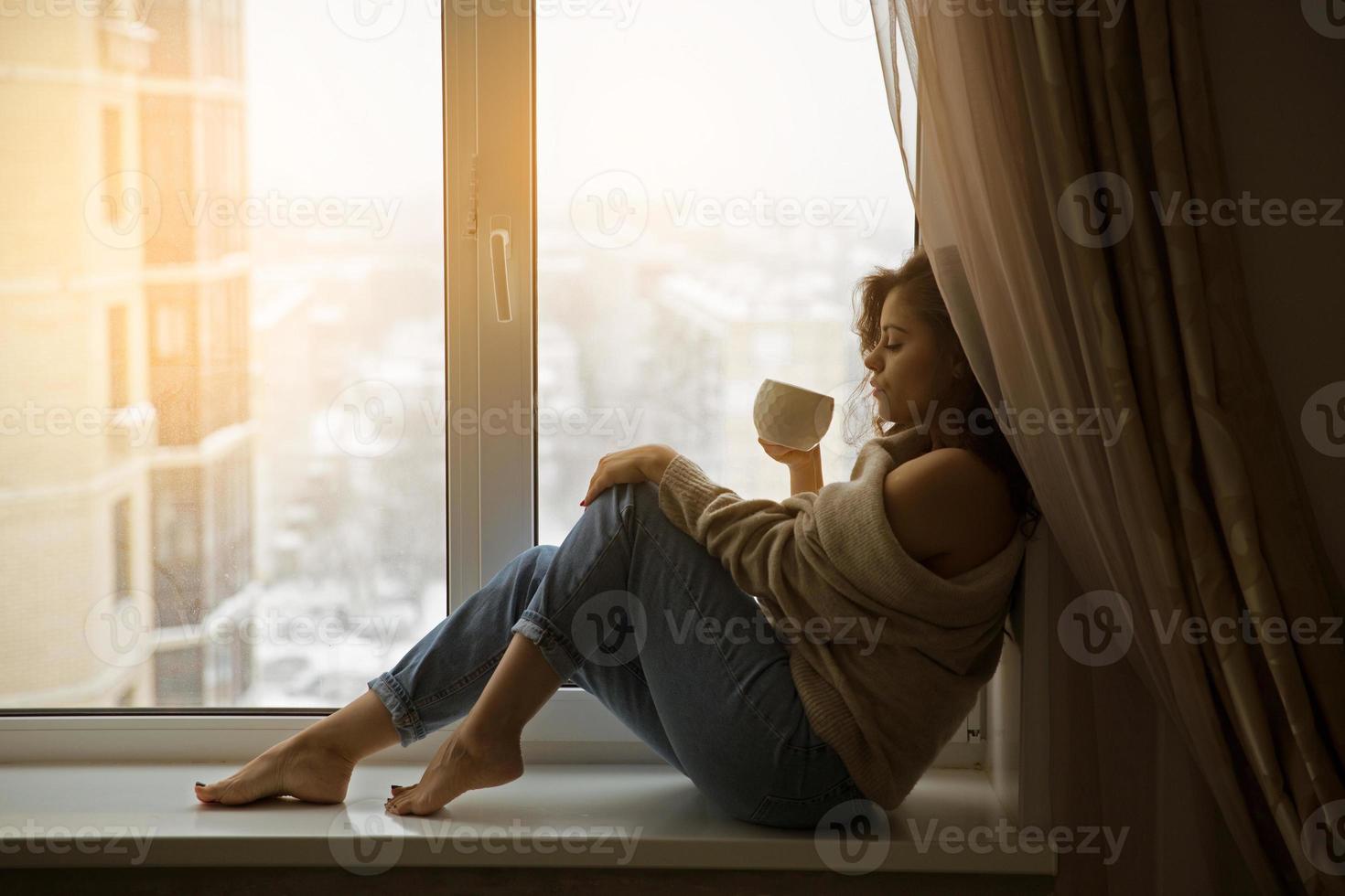 femme à la fenêtre buvant du café photo