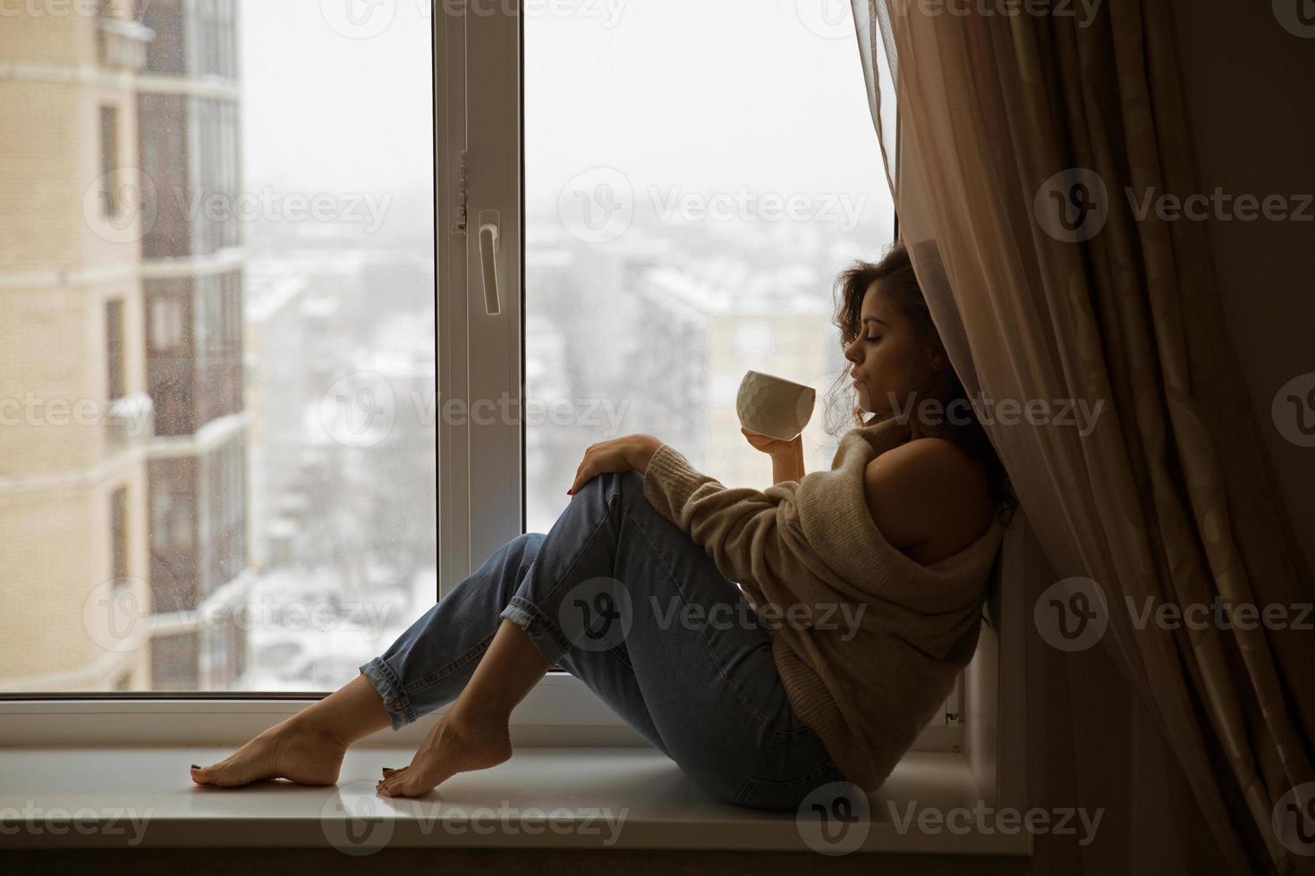 femme à la fenêtre buvant du café photo