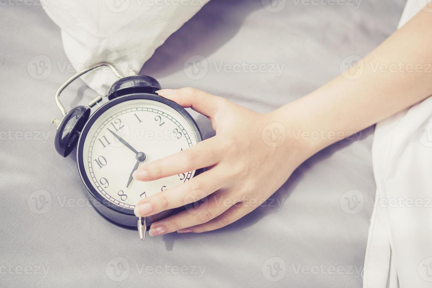 gros plan les mains de la femme éteignent le réveil le matin. photo