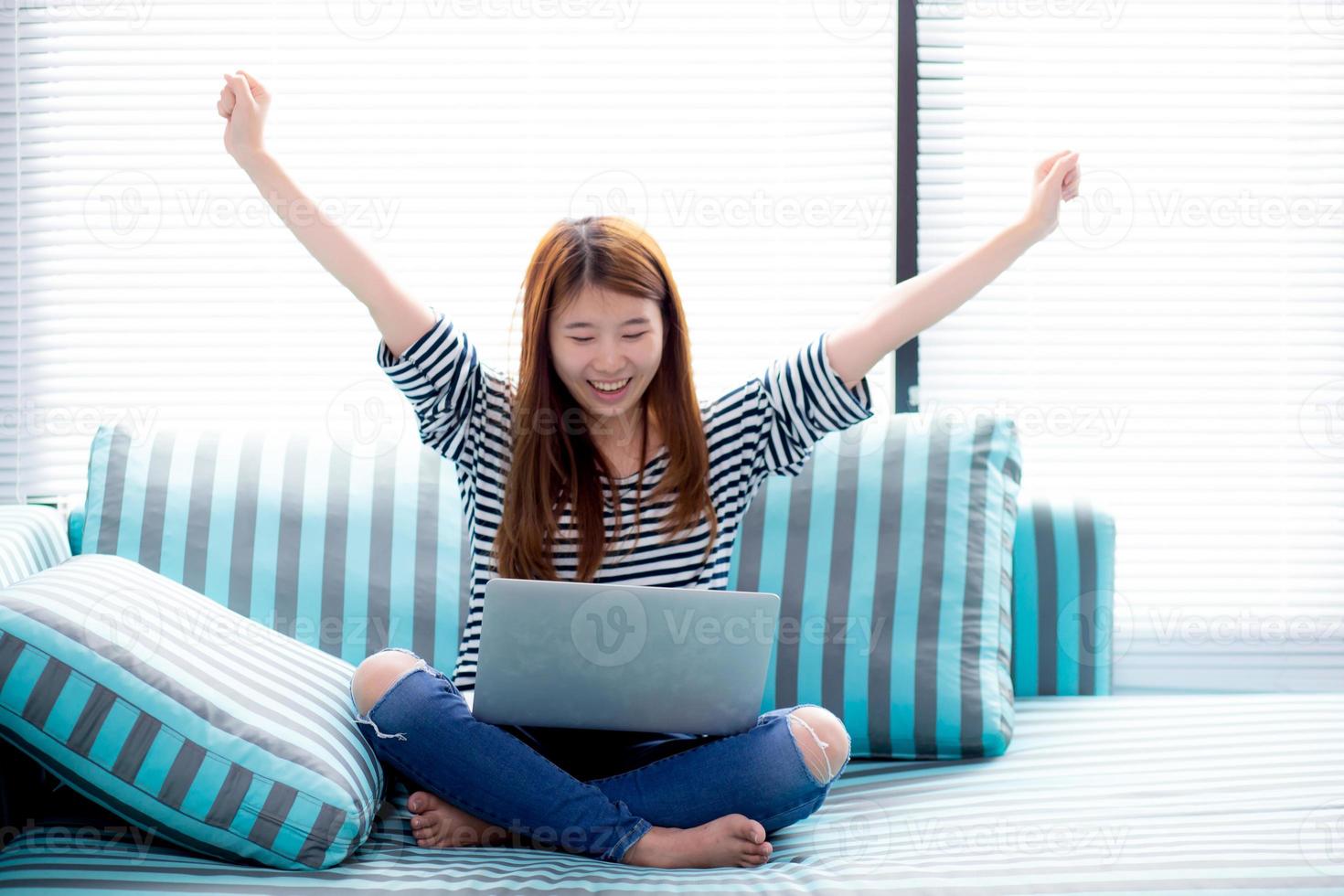 jeune femme asiatique utilisant un ordinateur portable travaille sur un canapé. photo