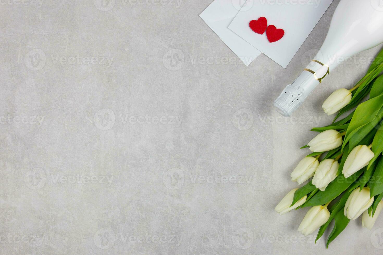 blanc tulipes fleurs avec Champagne, enveloppes et rouge cœurs sur lumière gris béton Contexte. la saint valentin, aux femmes, les mères jour, Pâques, anniversaire ou mariage, vacances plat poser. Haut voir. copie espace. photo