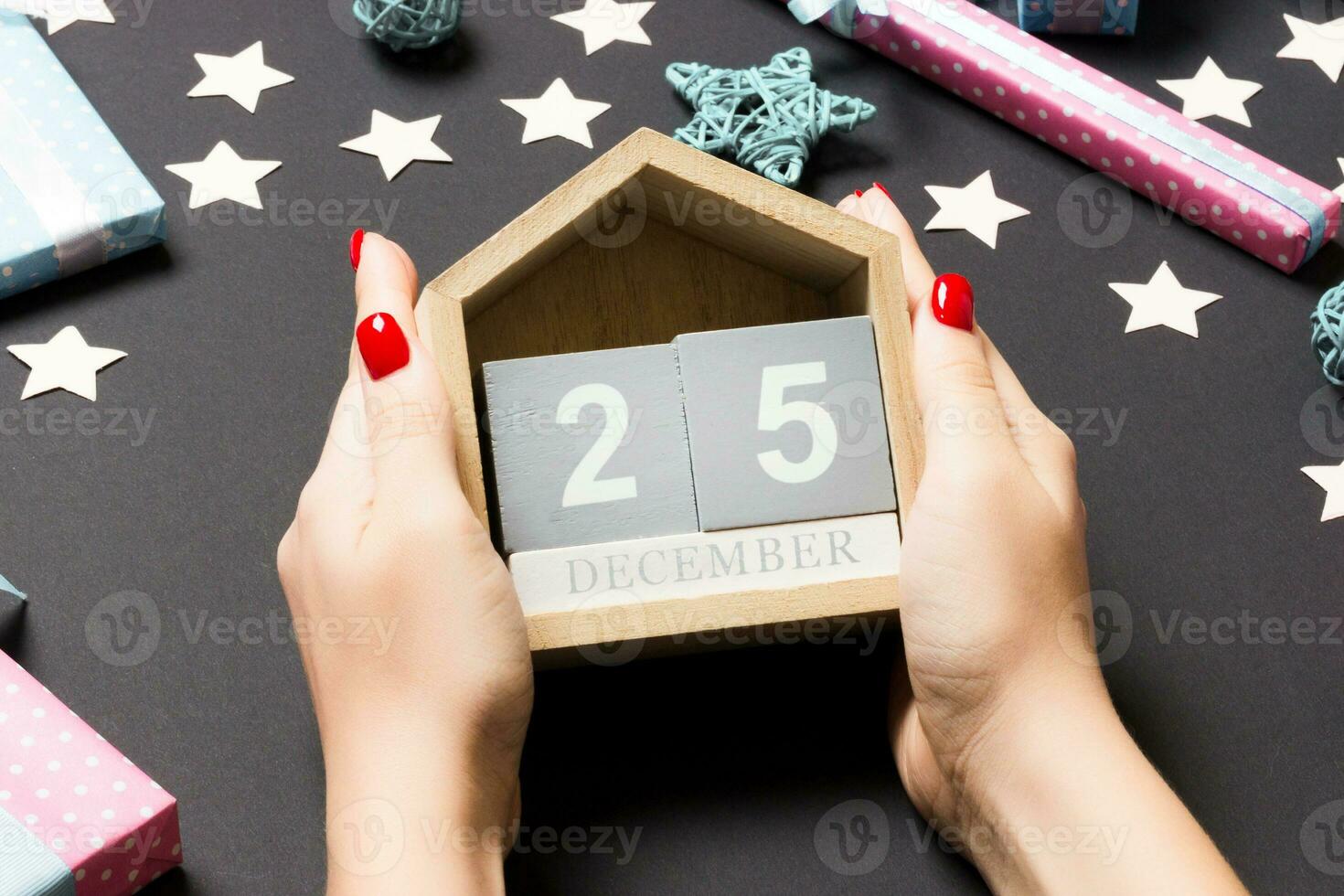 vue de dessus des mains féminines tenant le calendrier sur fond noir. le vingt cinq décembre. décorations de vacances. notion de temps de noël photo