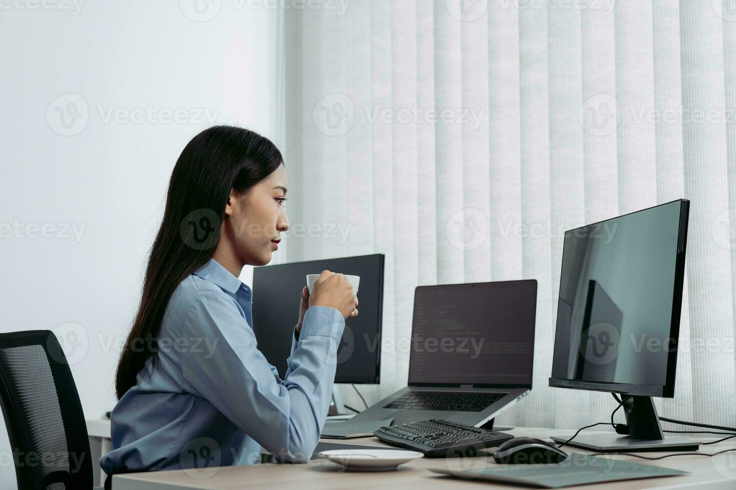 une femme asiatique buvait du café tôt le matin tout en contemplant le programme et le code sur l'écran de l'ordinateur. photo