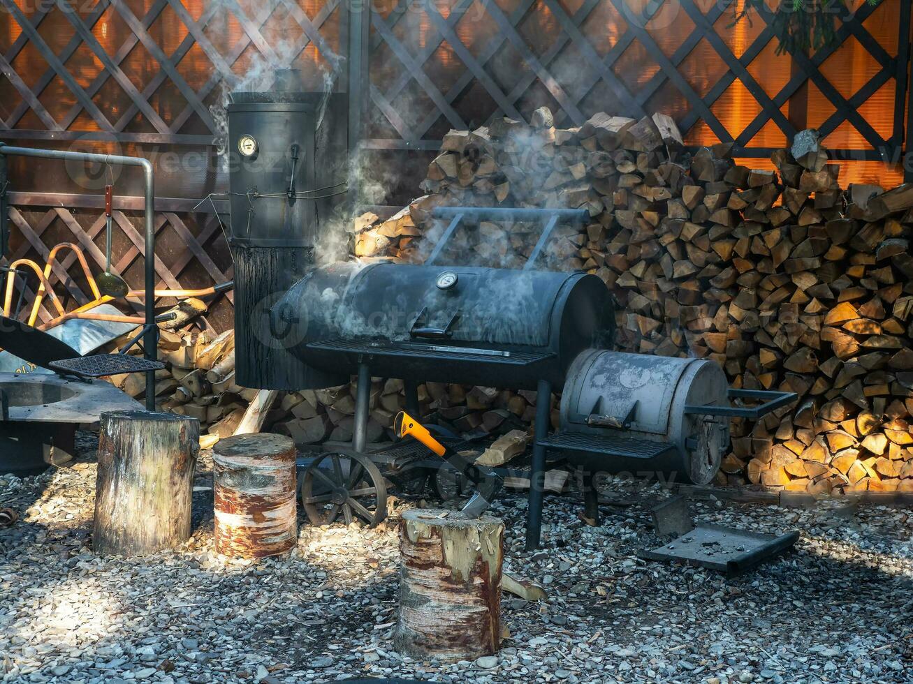 énorme bois fumeur des stands dans le ombre dans le Cour de le restaurant sur une ensoleillé été journée. photo