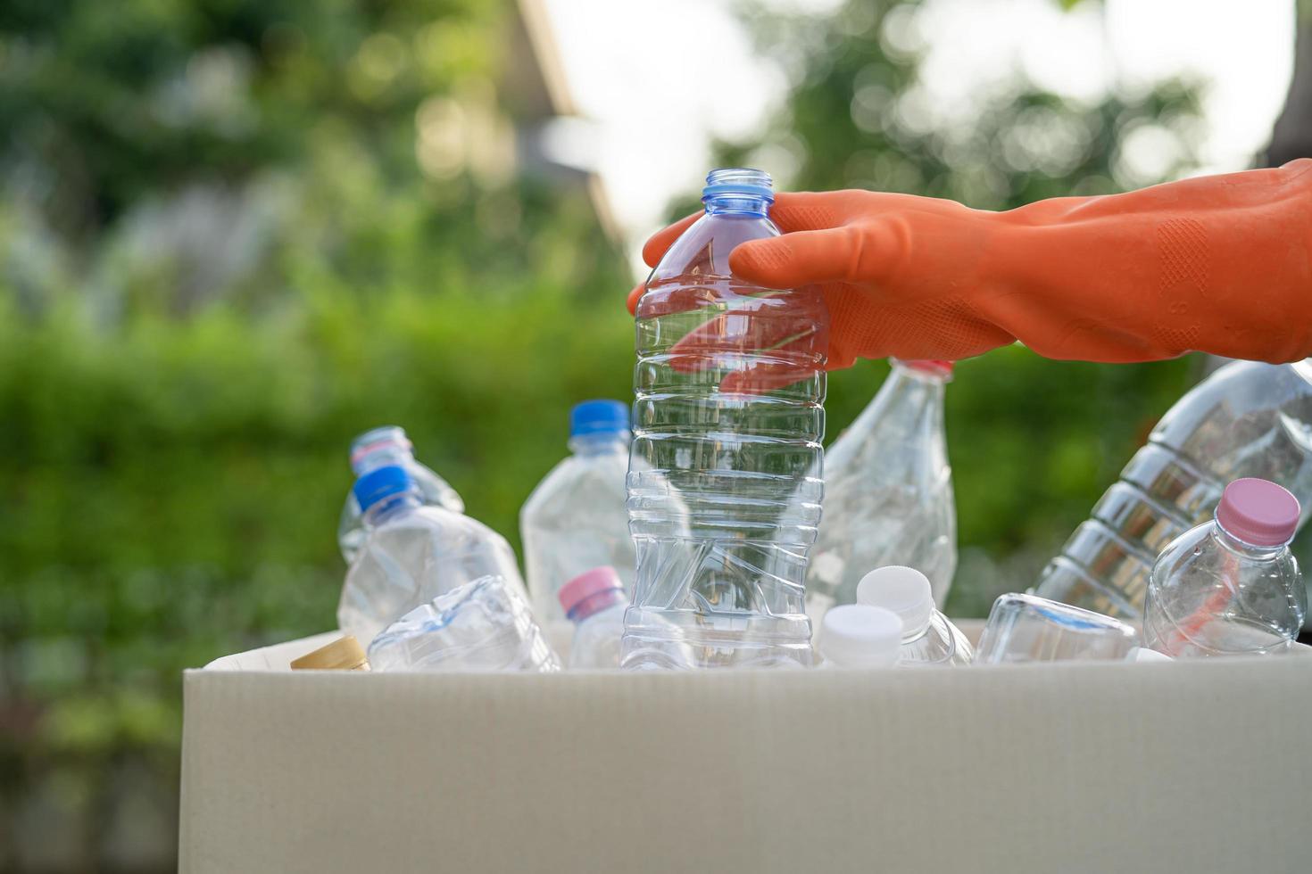 femme asiatique volontaire porter des bouteilles en plastique d'eau dans les ordures ménagères photo