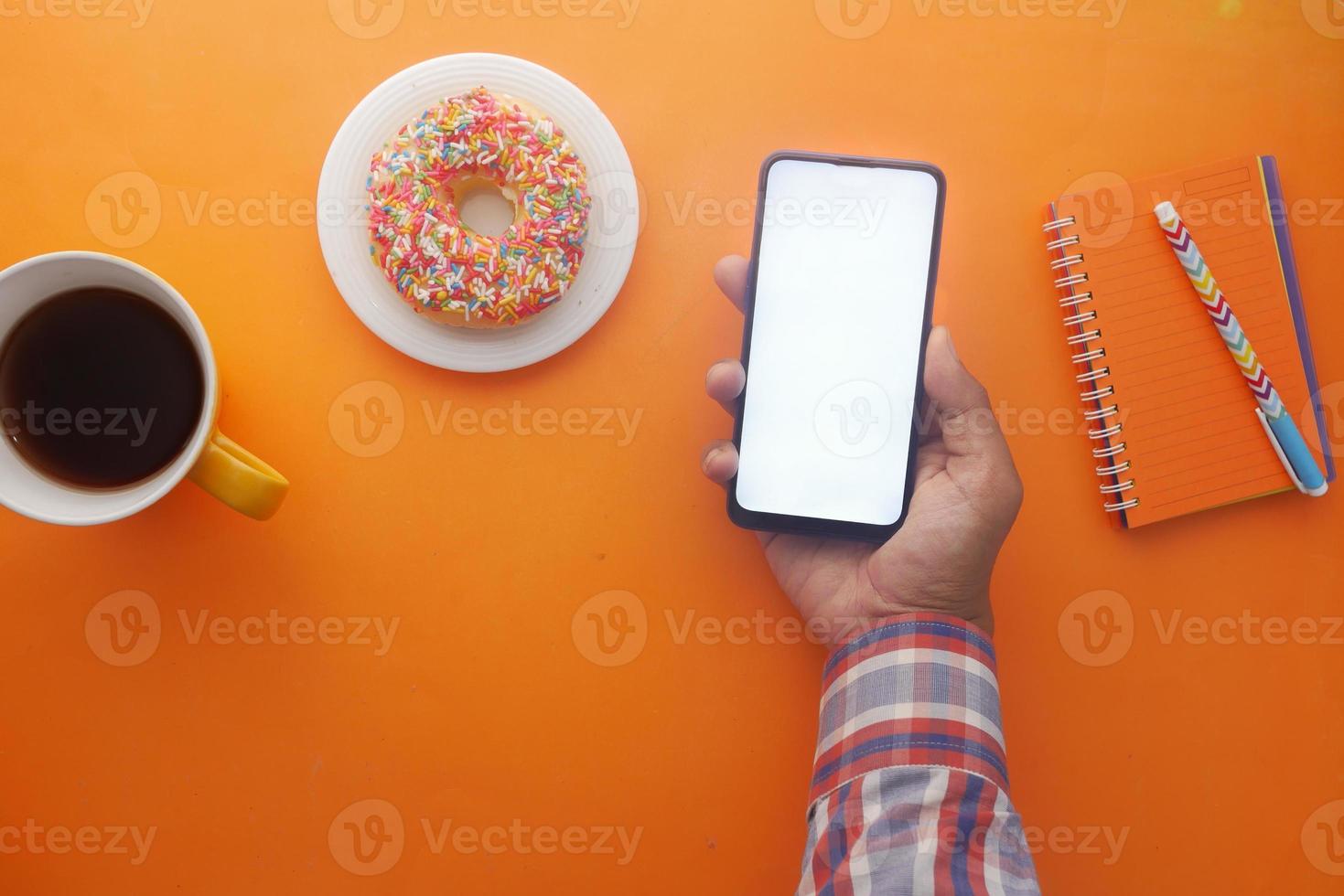 main de jeune homme utilisant un téléphone intelligent avec du thé et des biscuits sur la table photo