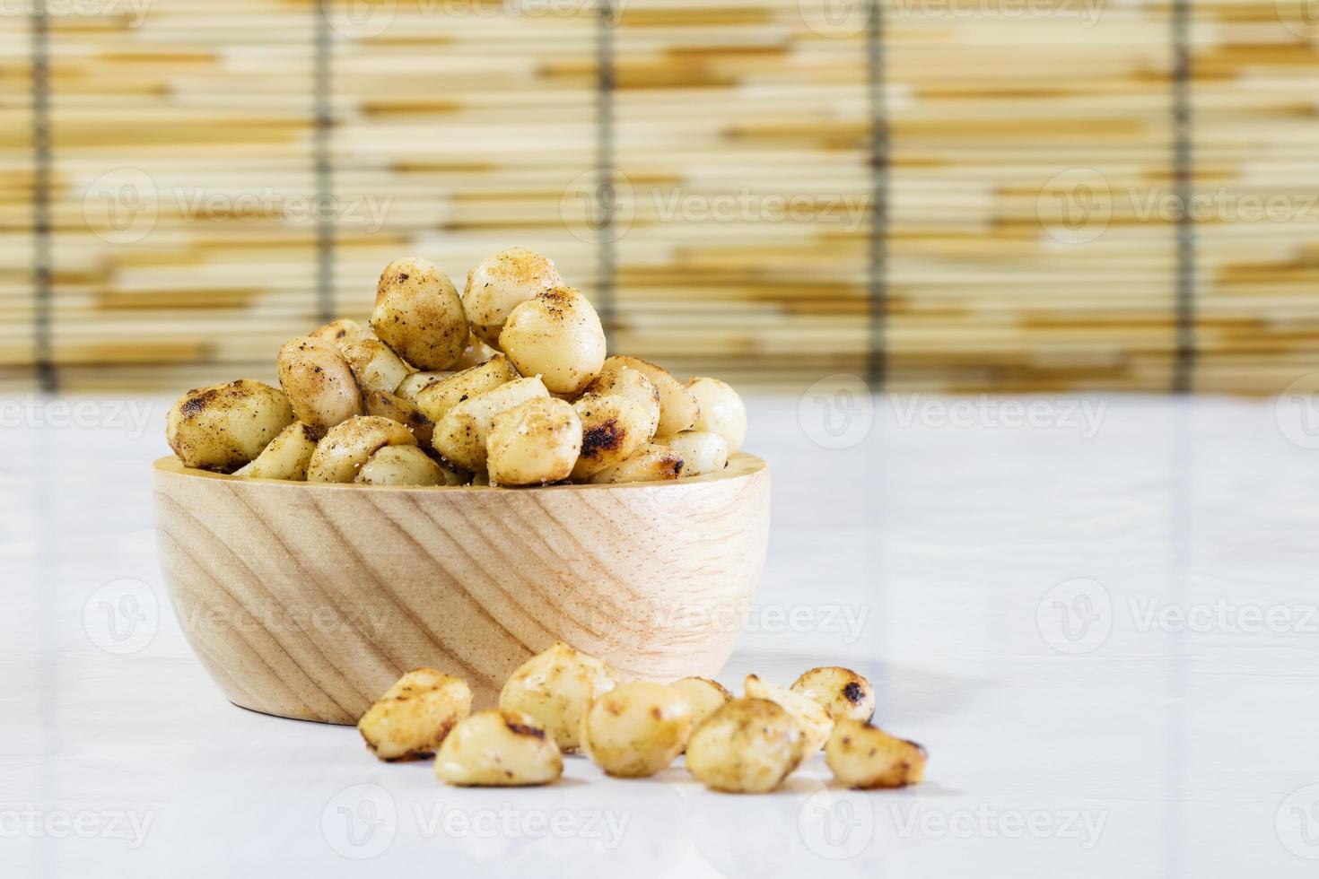 macadamia cuit au four avec du sel dans un bol en bois sur une table blanche photo