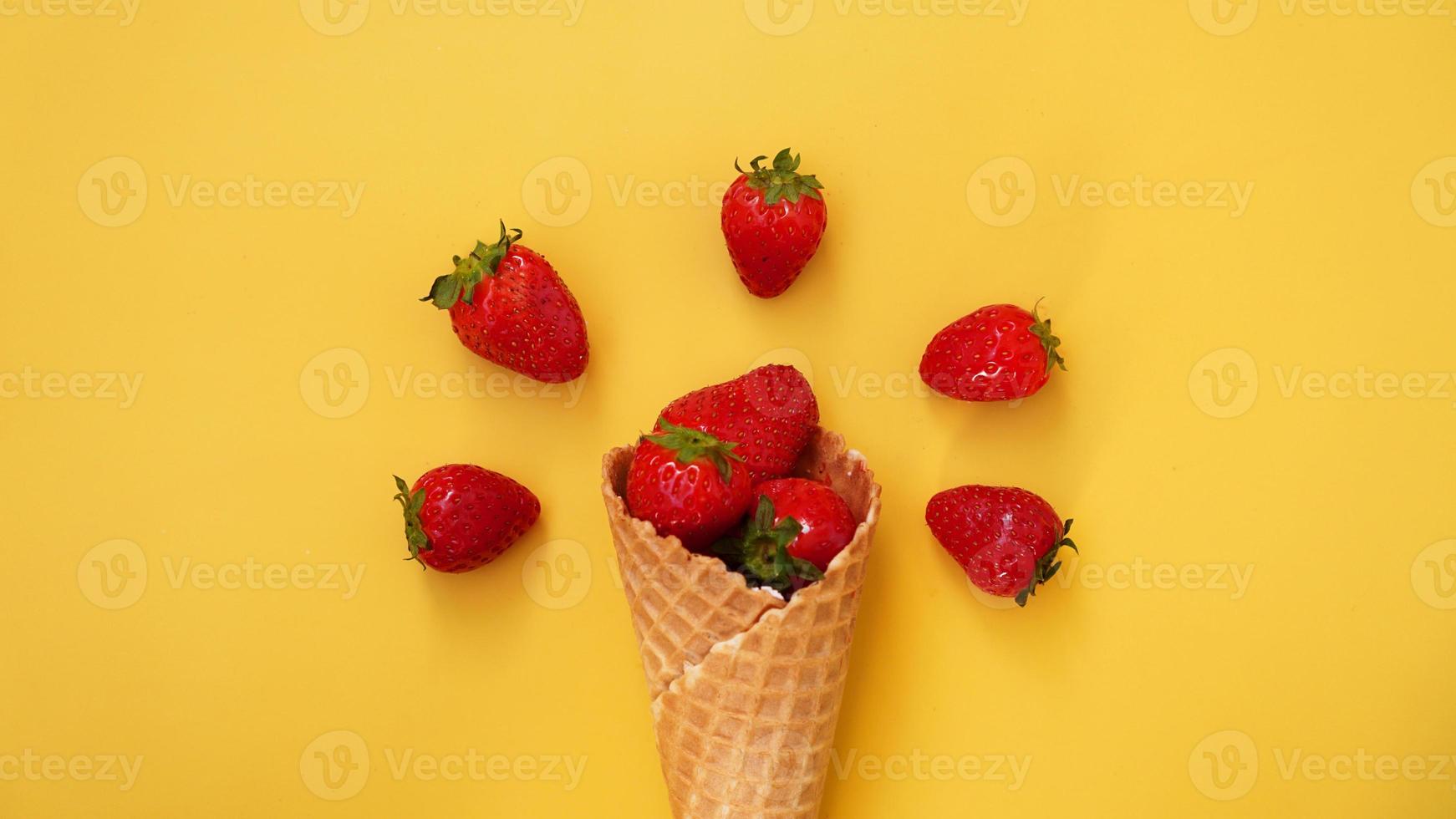 cornet de crème glacée aux fraises sur fond jaune photo