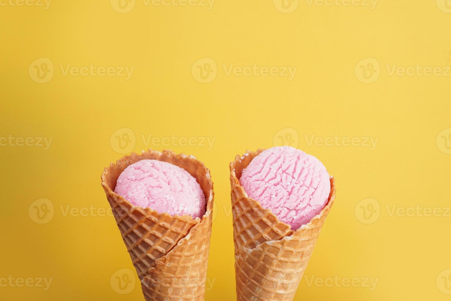 délicieuse crème glacée rose dans un cône sur fond jaune. photo