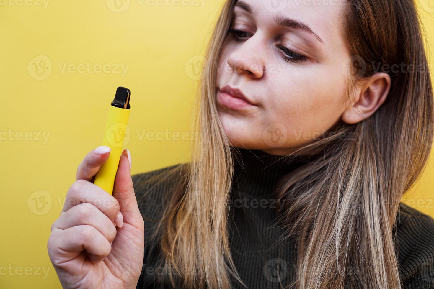 une jeune fille fume une cigarette électronique jetable photo