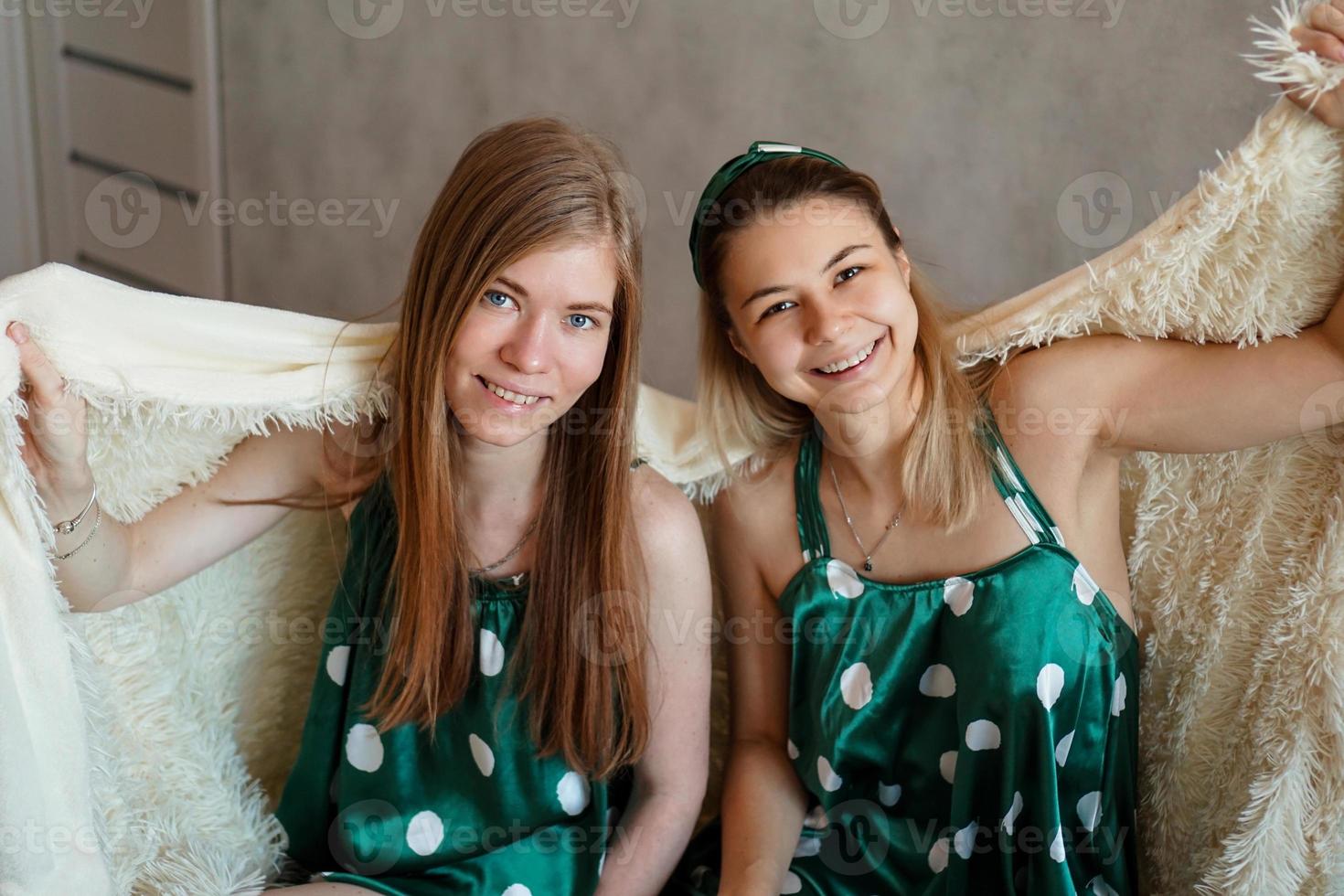 Deux jeune femme riante s'amusant en se cachant sous une couverture blanche photo