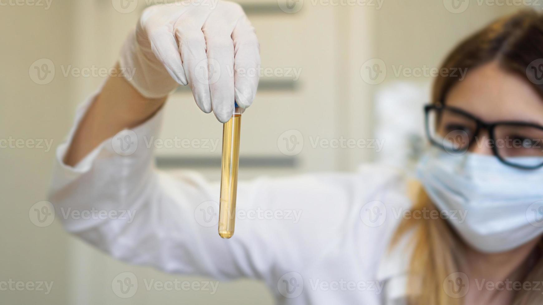 une femme tient un tube à essai avec un test d'urine photo