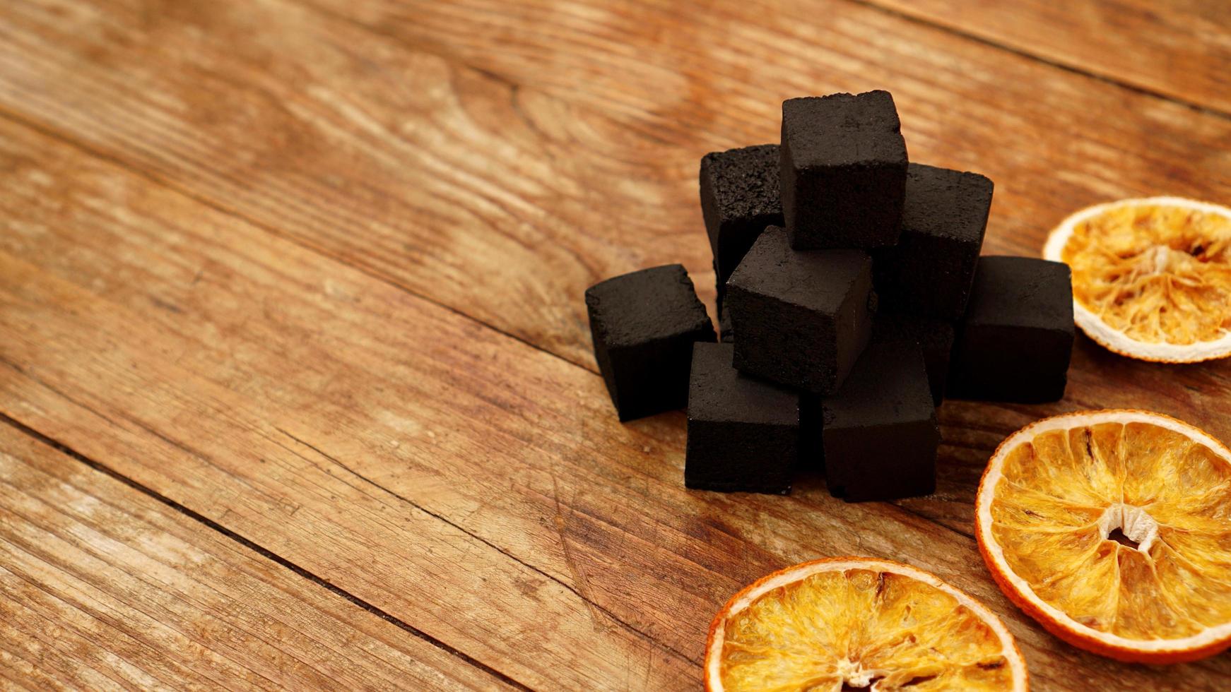 charbons pour narguilé sur fond de bois avec des oranges sèches photo