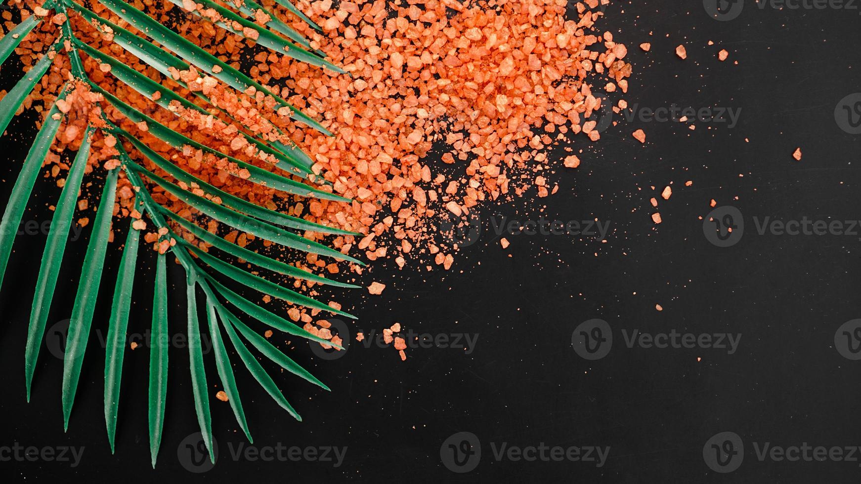 sel de mer orange sur fond noir. feuilles de palmiers tropicaux photo