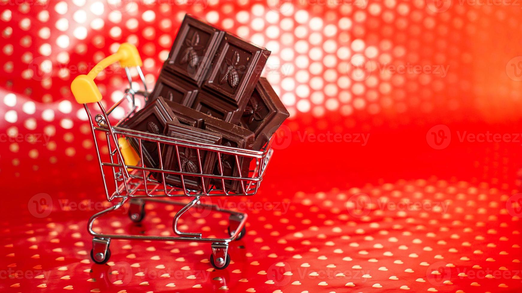 chocolat dans le caddie sur fond rouge. vente du 14 février photo