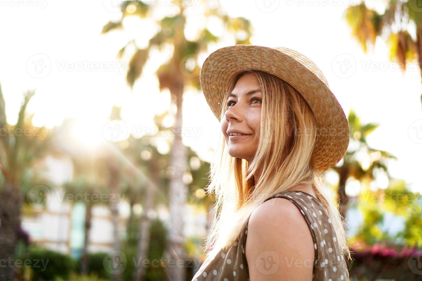 portrait d'une jeune blonde dans un chapeau sur un fond tropical photo