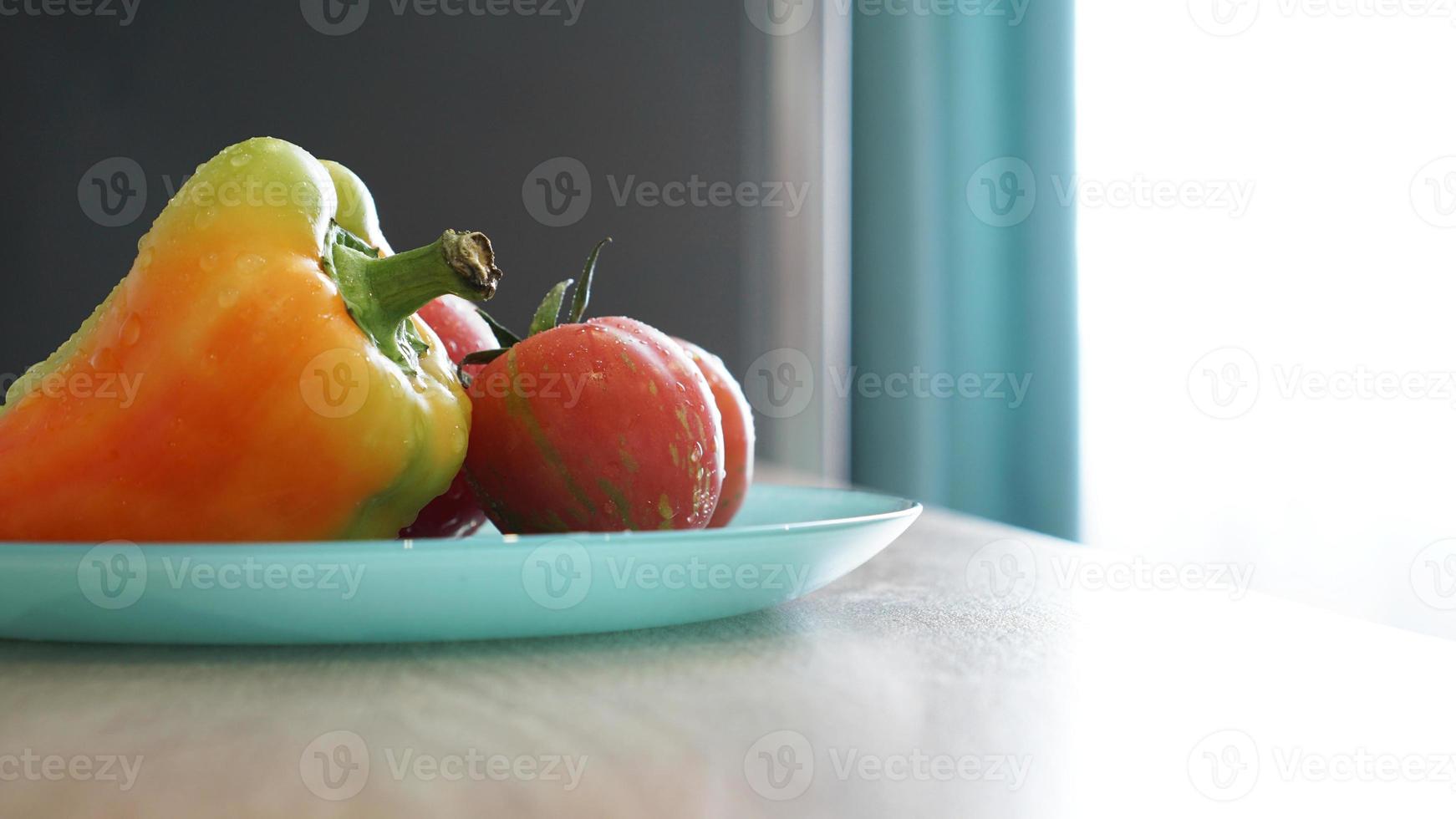 tomate et poivre sur une plaque bleue sur fond clair dans la cuisine photo