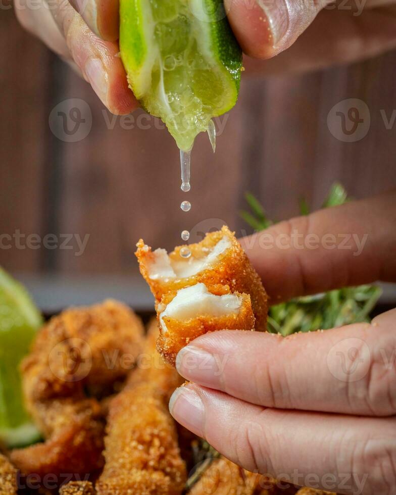 fermer de une personne main plongement citron vert dans frit poulet pépites photo