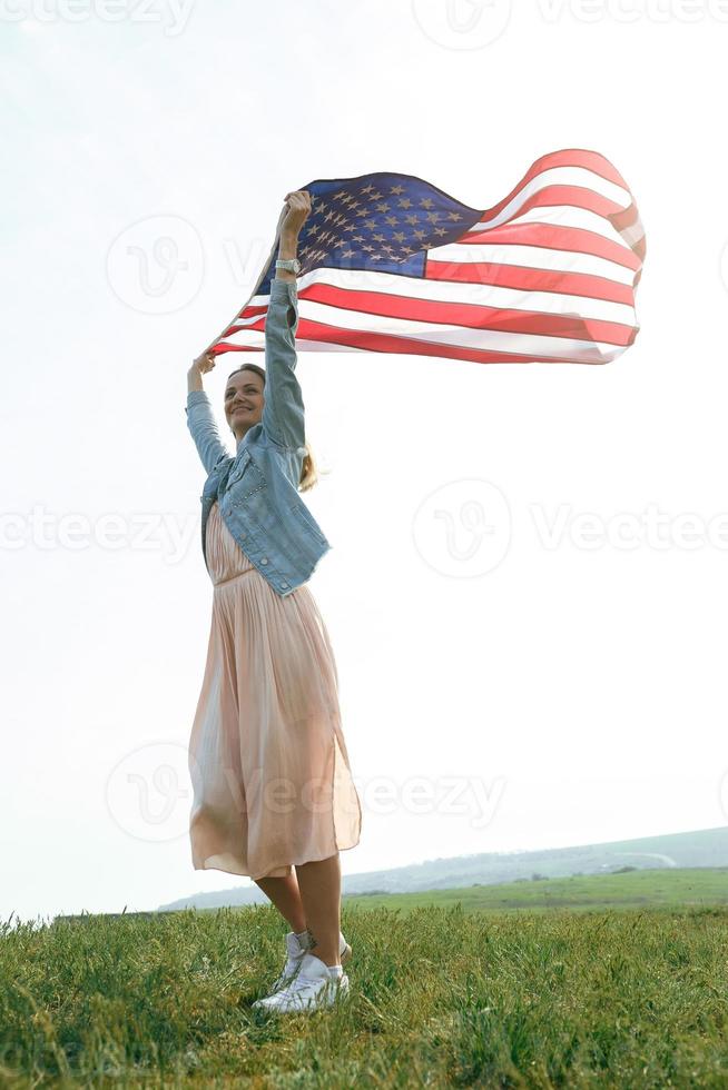 une fille vêtue d'une robe corail et d'une veste en jean tient le drapeau des états-unis photo