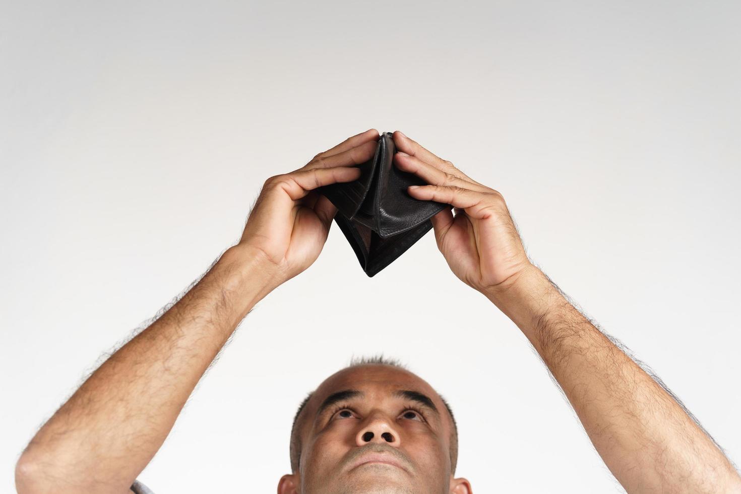 homme tenant la tête en bas et regardant à l'intérieur de son portefeuille vide. photo