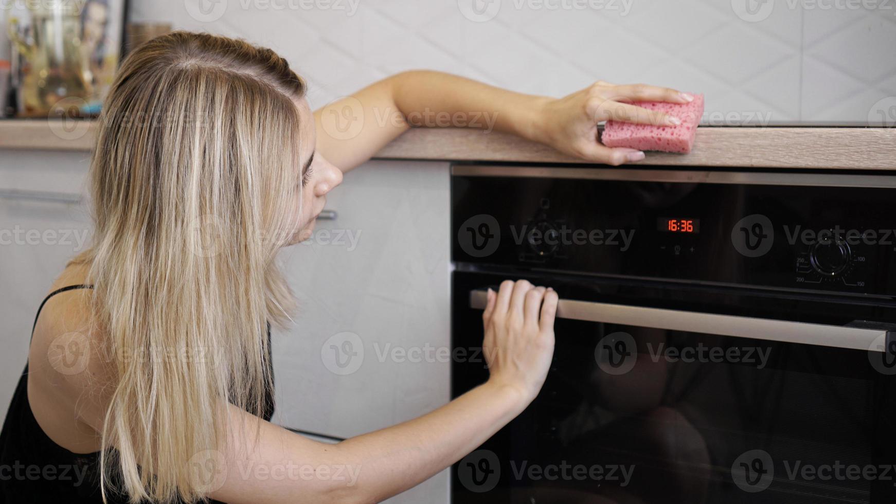 jeune femme nettoyant le four dans la cuisine. photo