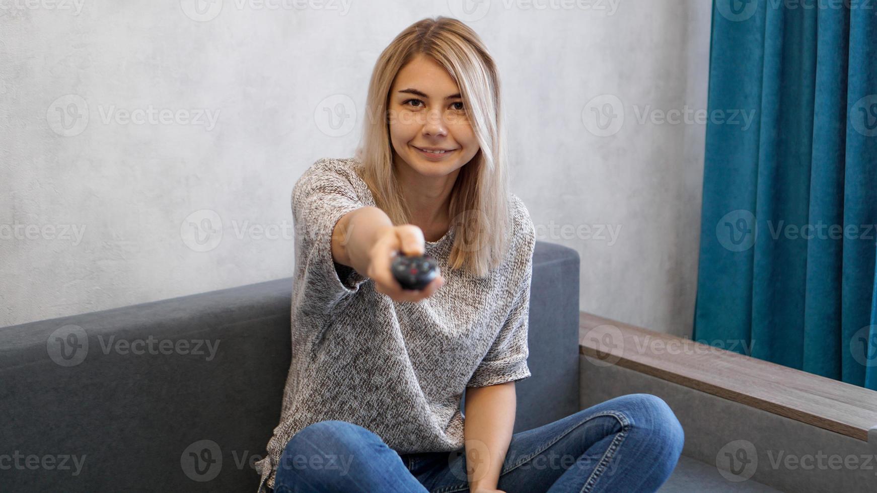 la jeune femme change les chaînes de télévision avec la télécommande photo