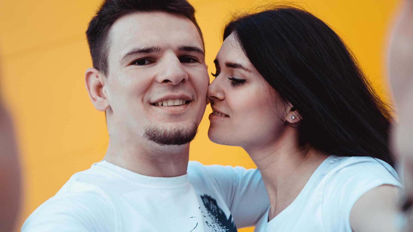 Jeune couple charmant faisant selfie sur smartphone sur fond jaune photo