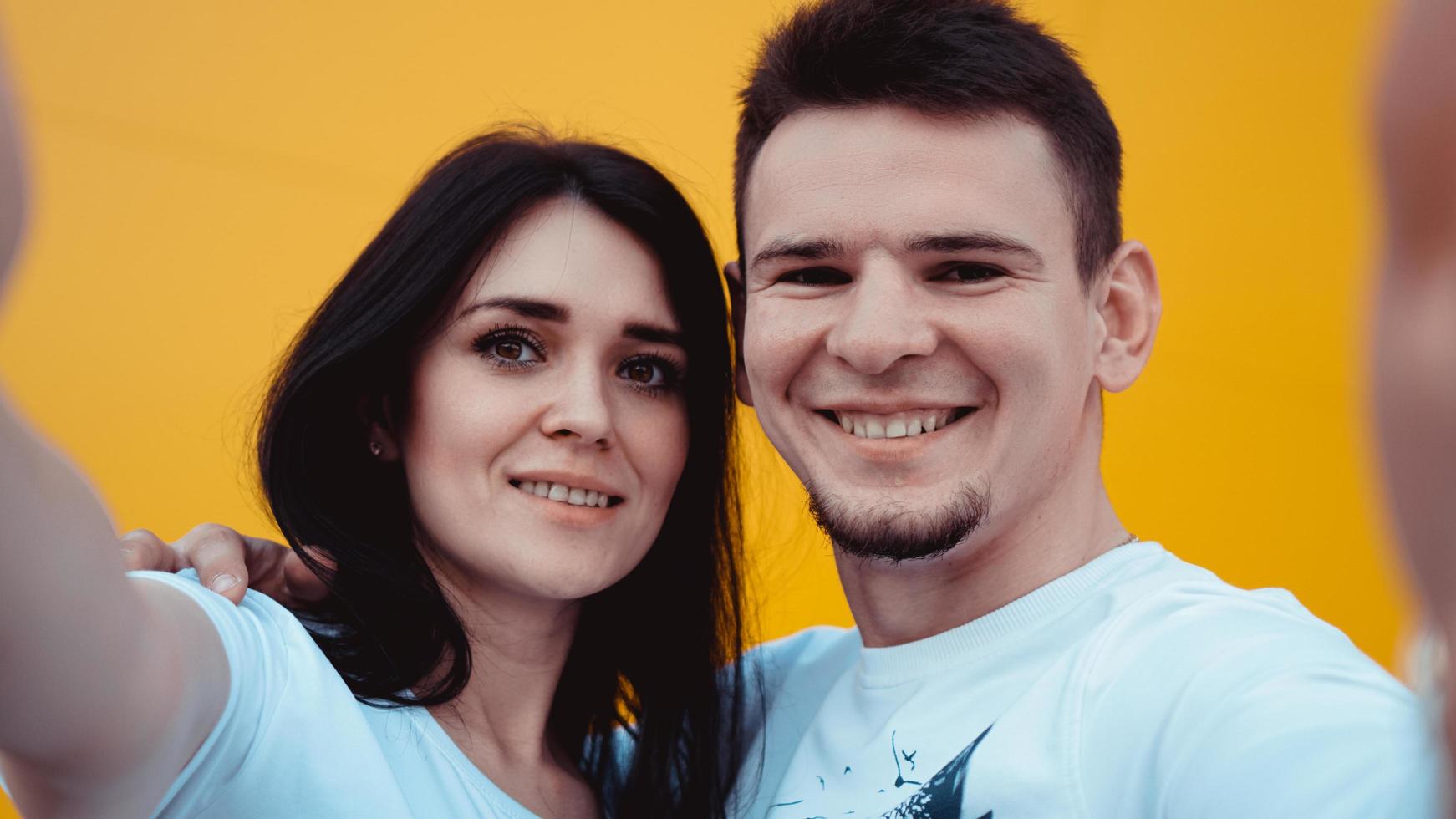 Jeune couple charmant faisant selfie sur fond jaune photo