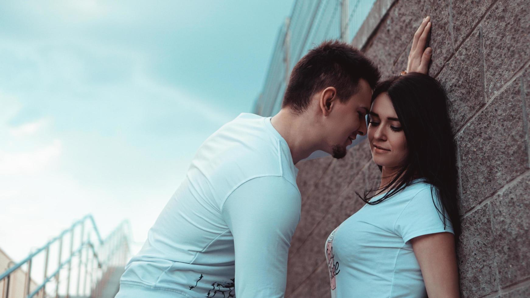 jeunes couples d'amoureux debout à côté du mur de briques photo