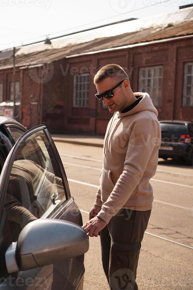 un jeune homme à côté de sa voiture par une journée ensoleillée photo