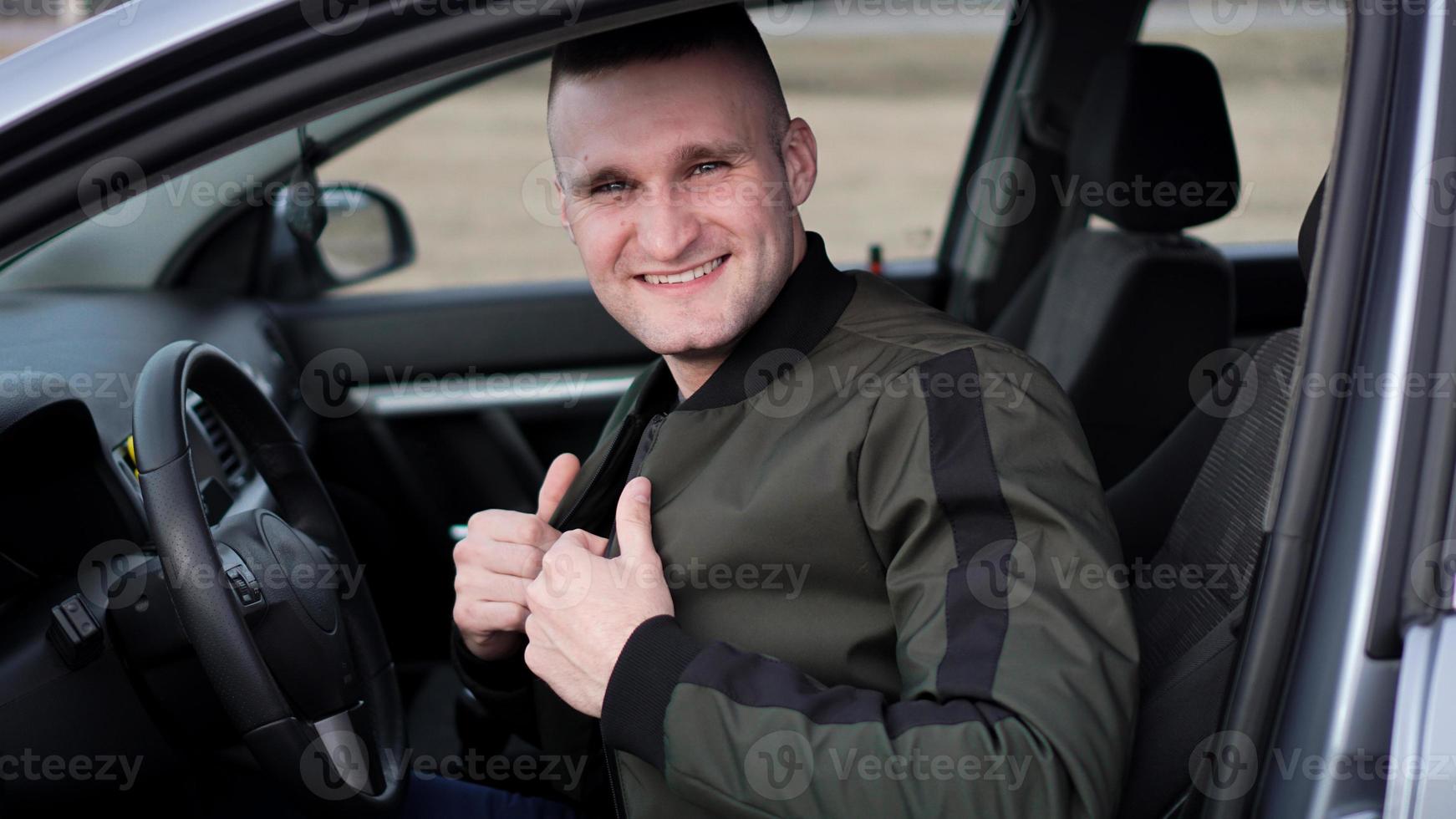 séduisant jeune homme souriant dans une voiture photo